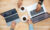 man-woman-two-laptops-drinking-coffee-together-top-view-african-caucasian-using-wooden-table-65973503
