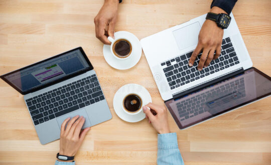 man-woman-two-laptops-drinking-coffee-together-top-view-african-caucasian-using-wooden-table-65973503