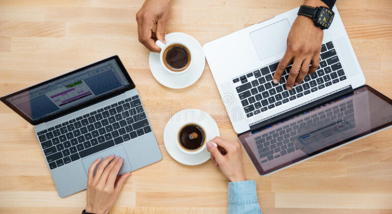 man-woman-two-laptops-drinking-coffee-together-top-view-african-caucasian-using-wooden-table-65973503
